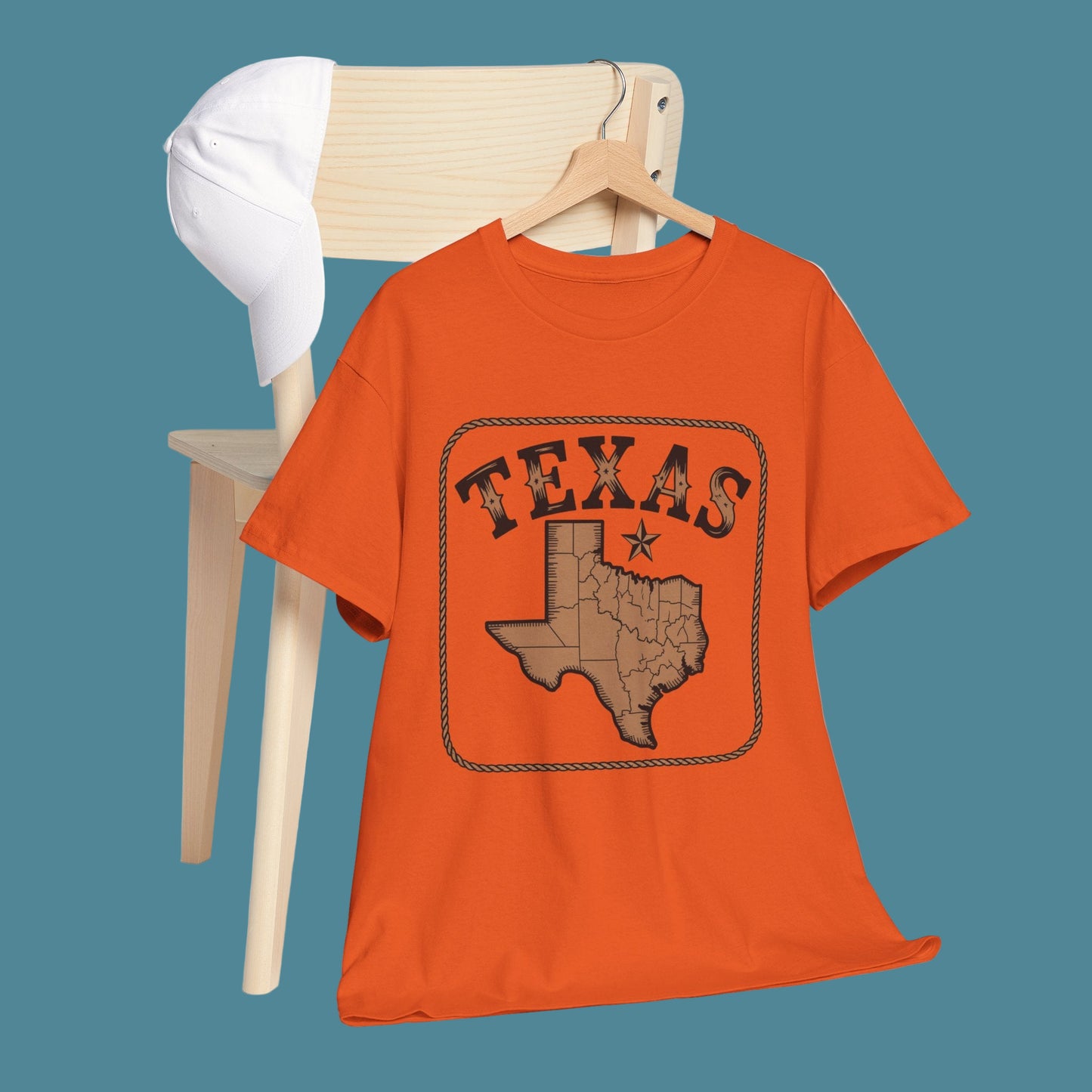 Orange t-shirt with Texas design on a wooden hanger against a white background